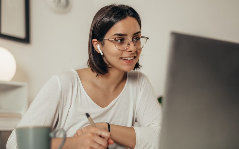 Estudiante mujer de Negocios Internacionales en modalidad virtual en clase toma apuntes.